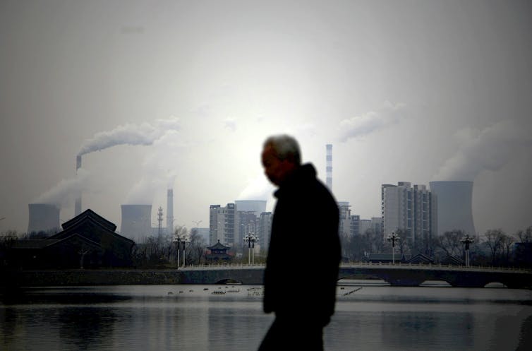 A man walking against an industrial skyline