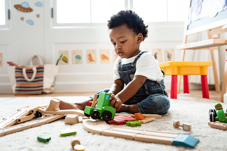A young boy plays with wooden toys on the floor.