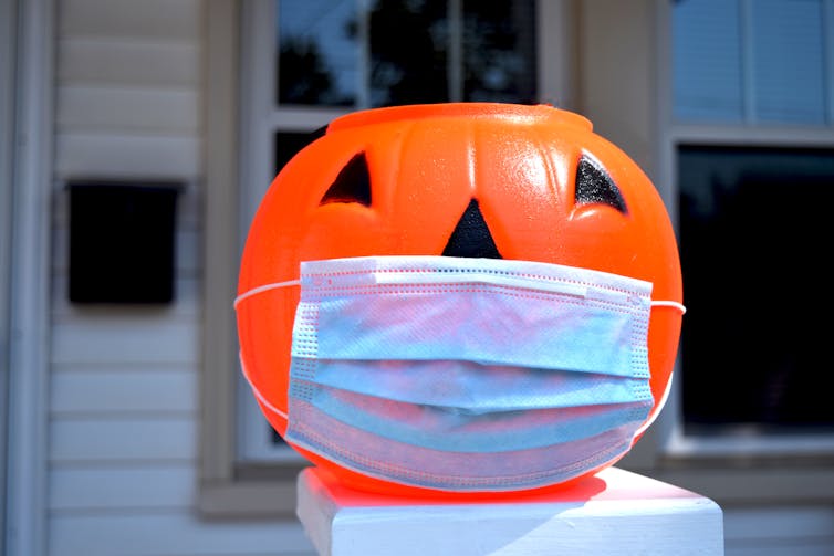 A Halloween pumpkin wearing a surgical mask