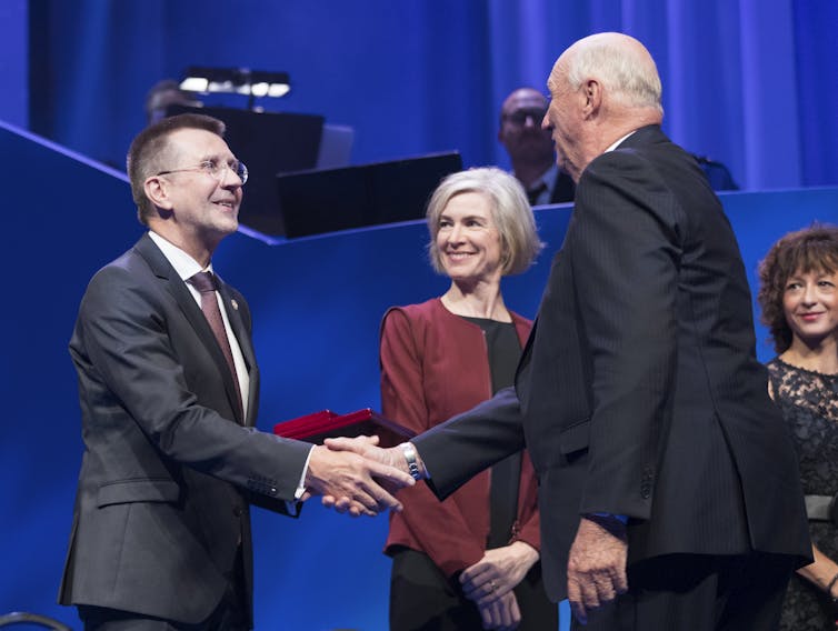 Virginijus Šikšnys shaking hands with prize awarded as Jennifer Doudna looks on.