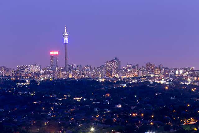 The skyline of Johannesburg at night with two prominent towers against a moody sky.