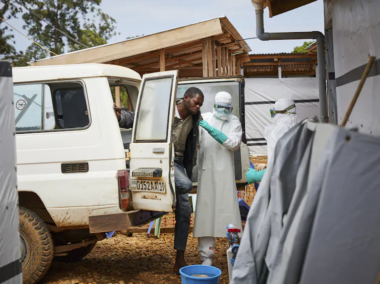 Health workers in the DRC assist a man potentially infected with Ebola.