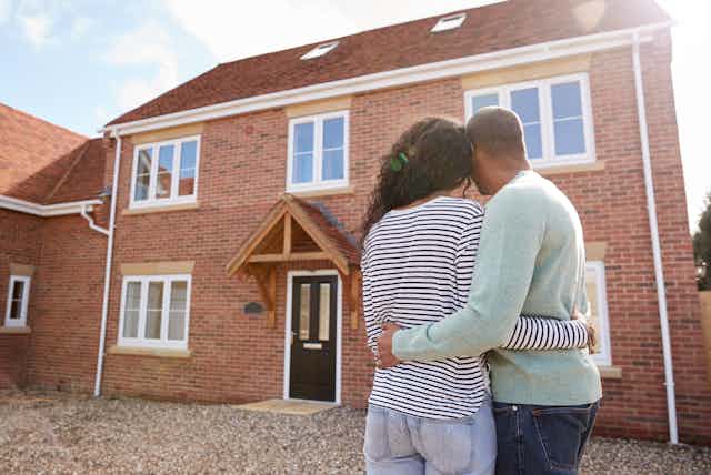 Couple embracing looking at new house