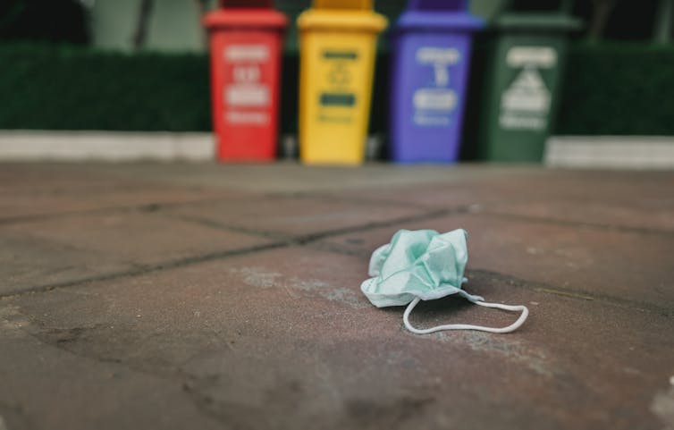 Face mask on the ground in front of bins