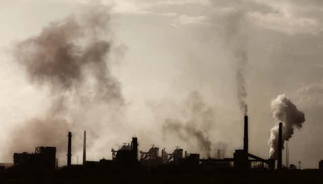 An industrila landscape with several chimneys emitting smoke and fumes.