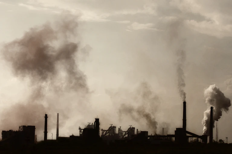 An industrila landscape with several chimneys emitting smoke and fumes.