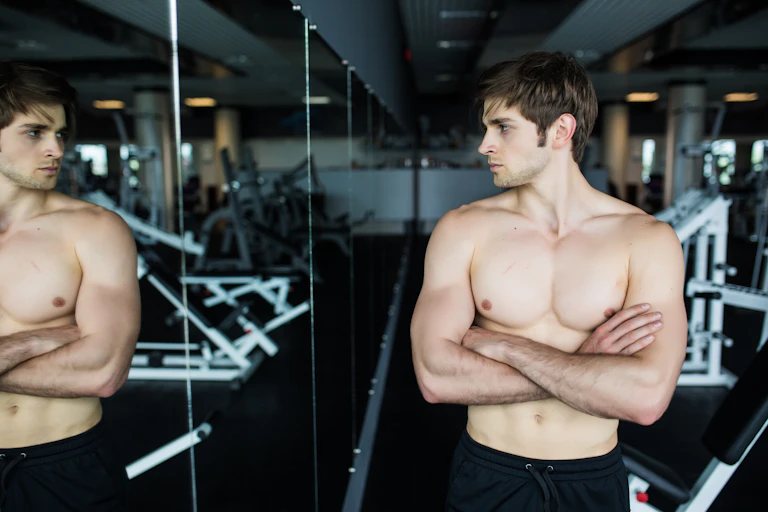 Young man looking at his muscles in a mirror.