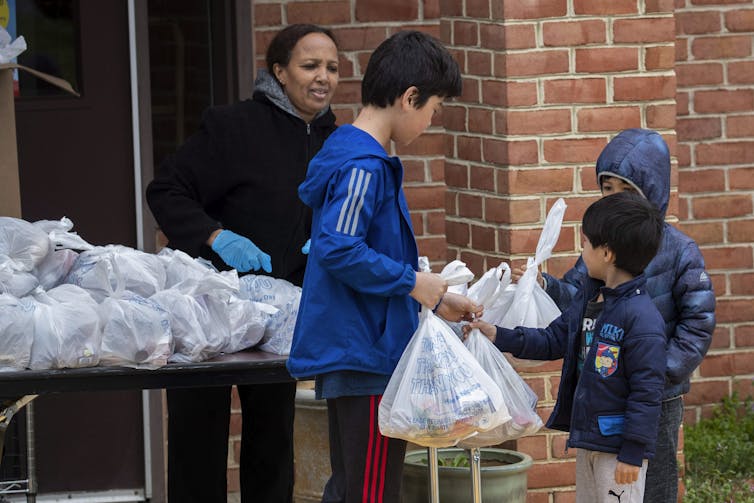 Chidren receive bags with meals in them at a school.