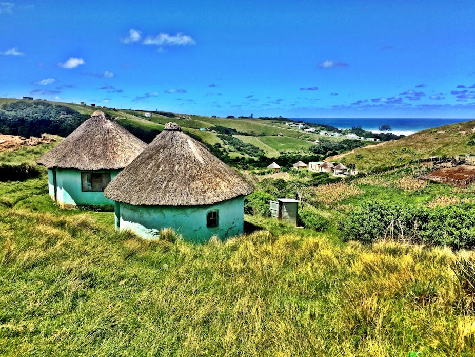 Xhosa huts on along South Africa's Wild Coast with the mountains and the ocean and a backdrop. 