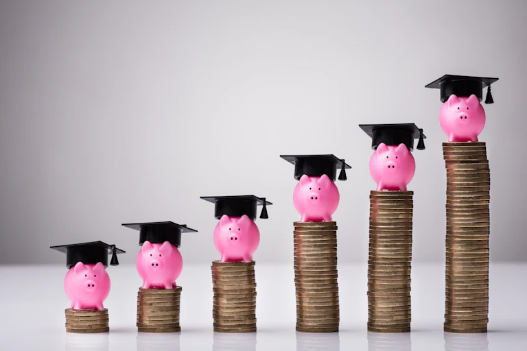 A row of ascending coins topped with piggy banks in graduation caps.