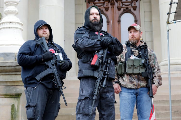 Armed men stand on the steps of the Michigan capitol building.