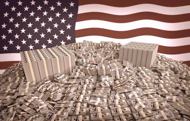 Stacks of dollar bills in front of an American flag