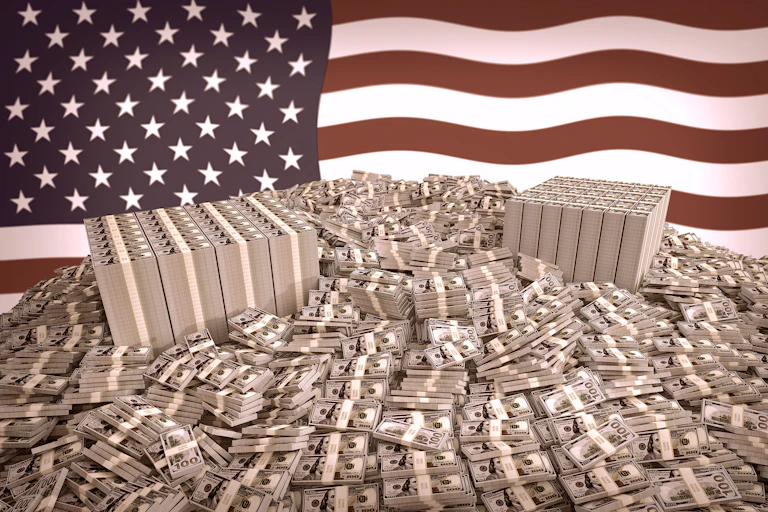 Stacks of dollar bills in front of an American flag