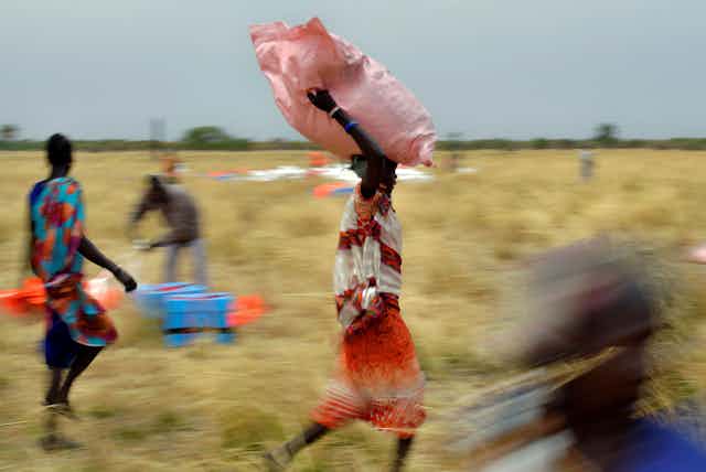 Villagers pick up sacks of air-dropped food .
