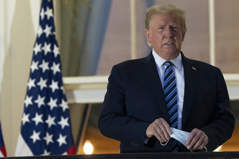 President Trump holds a mask on his return from Walter Reed Medical Center on Oct. 5, 2020.