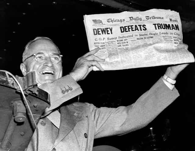 Harry Truman holding a newspaper with the headline "DEWEY DEFEATS TRUMAN"