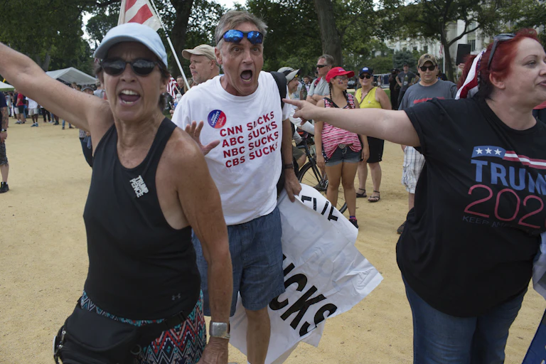A Trump supporter's t-shirt says "CNN SUCKS, ABC SUCKS, NBC SUCKS, CBS SUCKS."