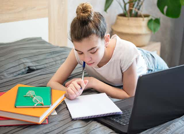 Young girl studying on bed.