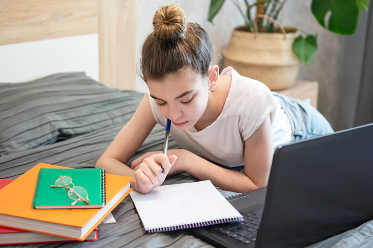 Young girl studying on bed.