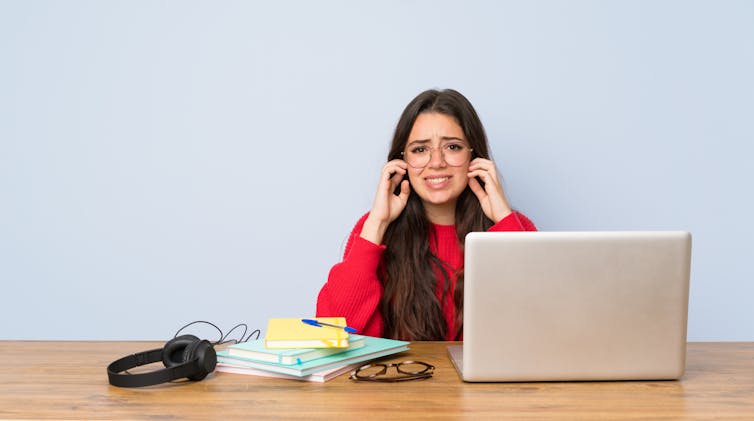 Teenager covering ears while studying