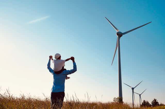 Man and child look at wind turbines