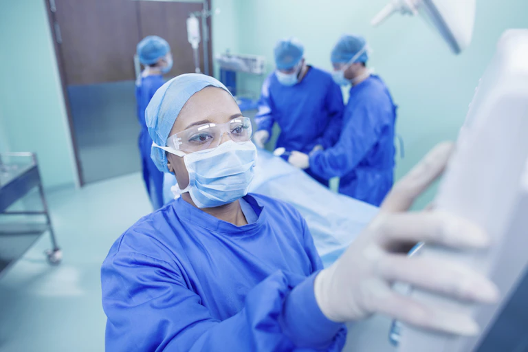 Health worker adjusting checking monitor vital signs dressed in safety gown scrubs