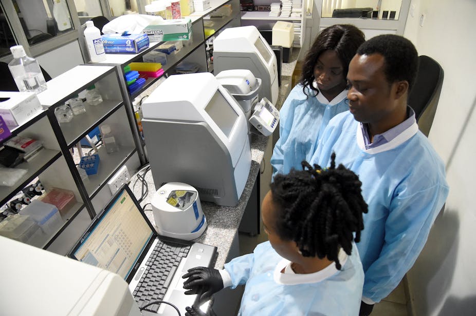 Three people in lab coats surrounded by scientific equipment