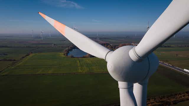 A close-up view of a wind turbine with the countryside behind it.