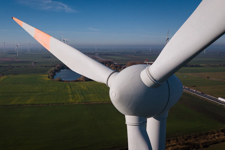 A close-up view of a wind turbine with the countryside behind it.