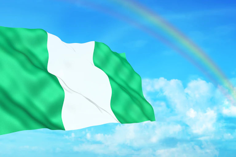 An illustration of a Nigerian flag flying, with clouds and a rainbow in the background