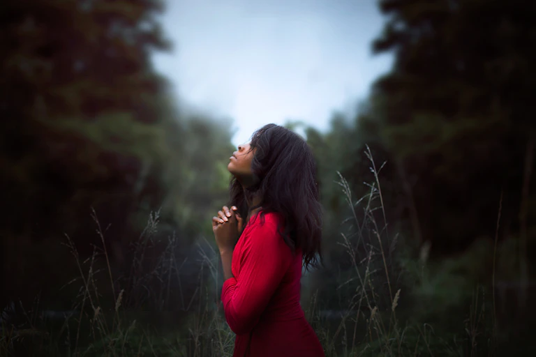 Woman wearing red sweatshirt closes eyes and wishes.