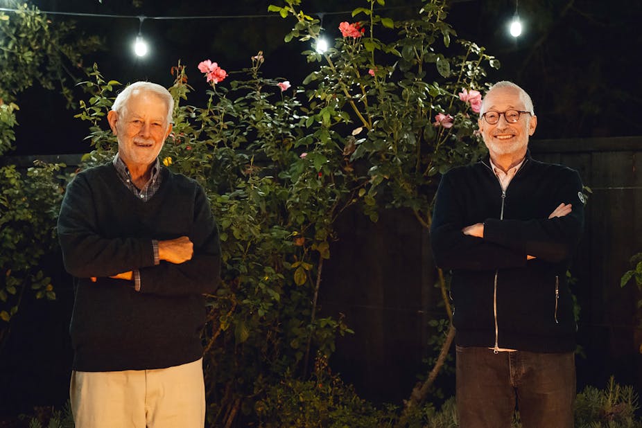 Robert Wilson and Paul Milgrom posing in front of some bushes