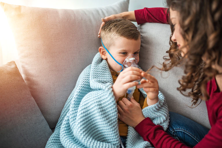 Una madre atiende a un niño con respirador y mantita.