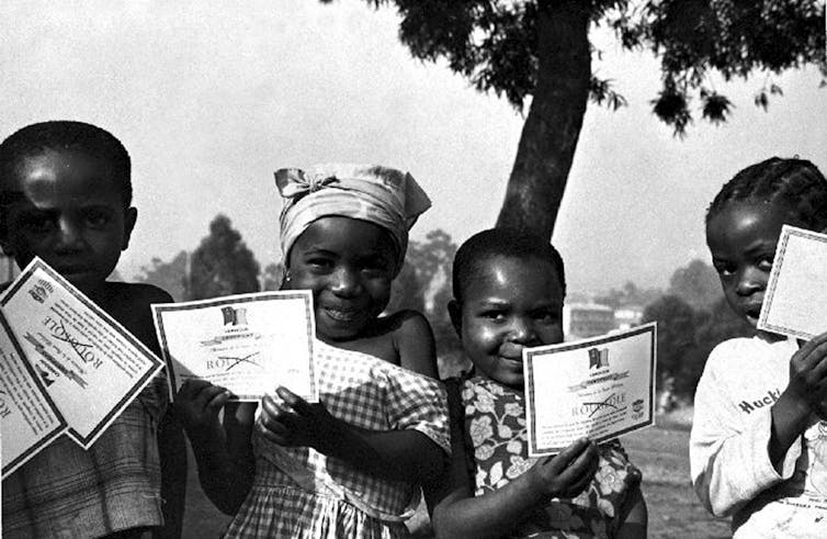 Unos niños muestran certificados de vacunación de la viruela