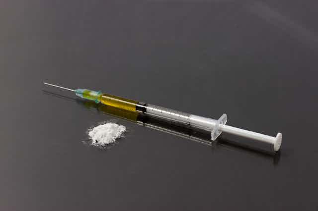 A syringe next to some white powder