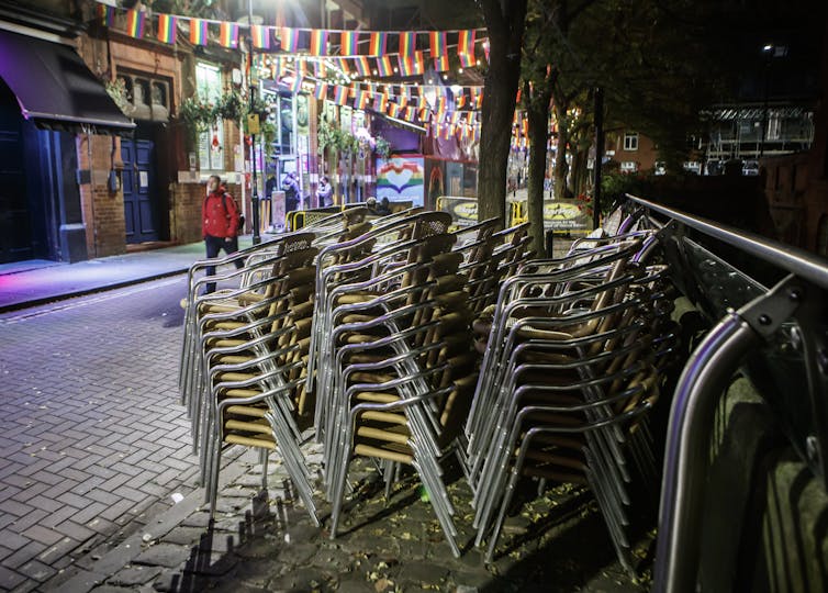 Three stacks of chairs on a street at night-time.