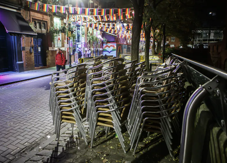 Three stacks of chairs on a street at night-time.