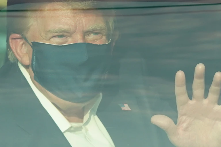 President Trump waves to supporters as he drives drives past them in a motorcade outside of Walter Reed Medical Center.