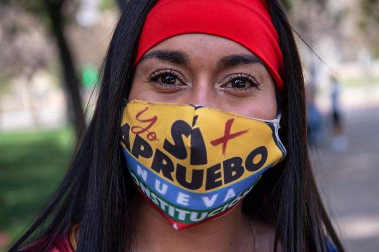 A woman in a face mask reading 'Sí apruebo.'
