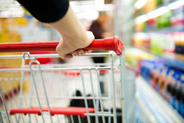 Hand pushing shopping trolley through supermarket
