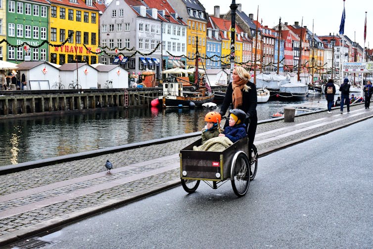 A woman takes her two kids in a cargo bike, in Copenhagen.