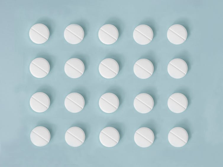 White aspirin pills in a grid on a blue background