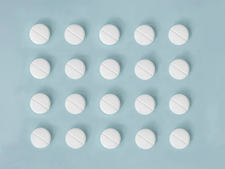White aspirin pills in a grid on a blue background