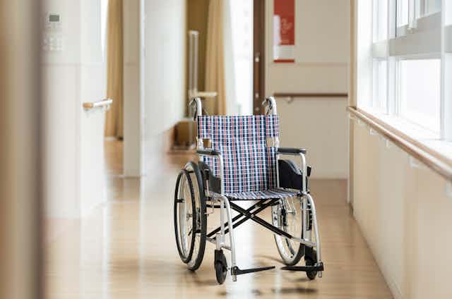 A wheelchair sits in the corridor of a nursing home.