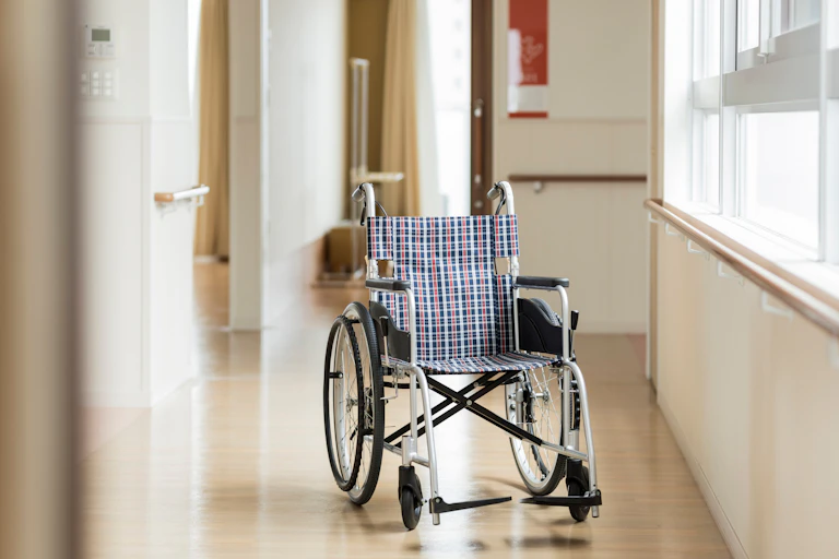 A wheelchair sits in the corridor of a nursing home.