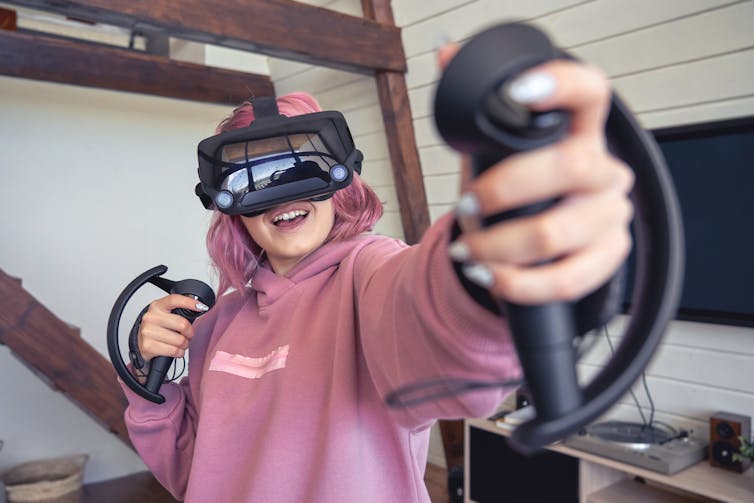 Excited teen hipster girl playing virtual reality video game wear vr goggles headset.