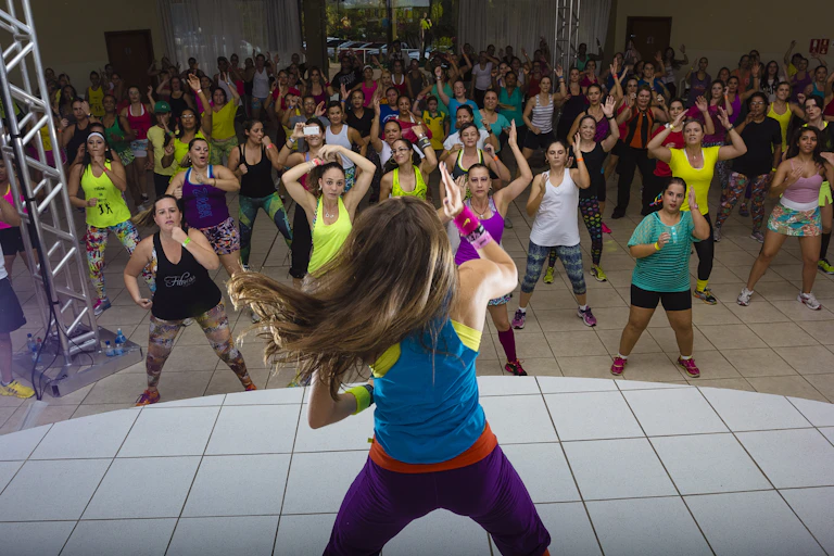 Woman on stage leads large dance class