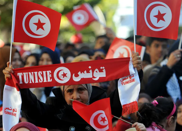 Une femme tient le drapeau national tunisien