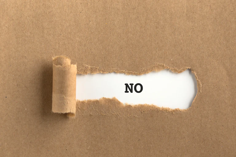 Un NO de imprenta tras un papel rasgado