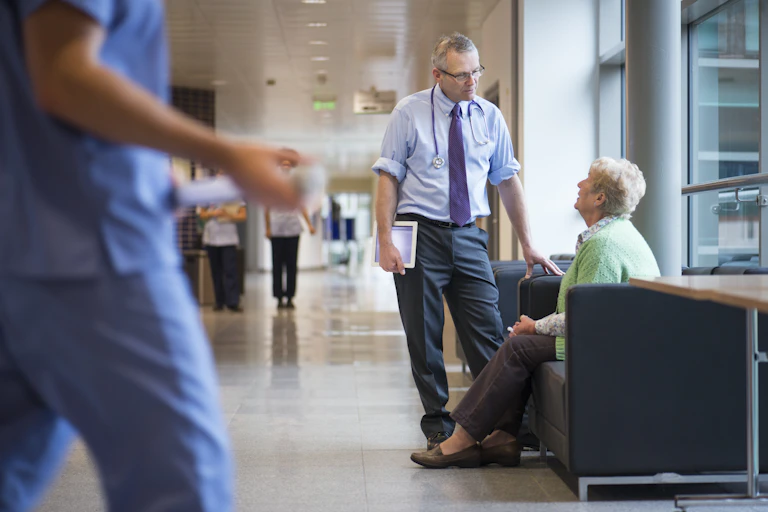 Standing doctor speaks to seated woman
